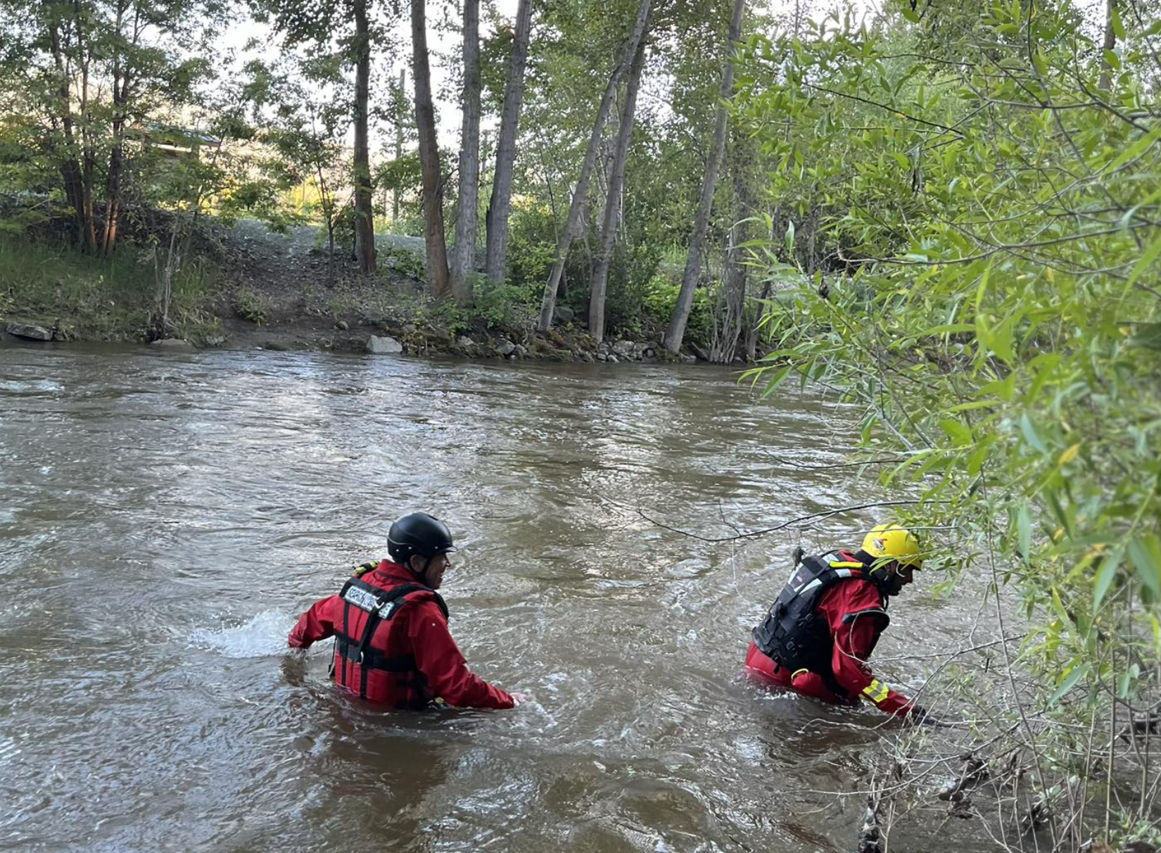 Two people in Central Okanagan Search and Rescue members walking through a creek.